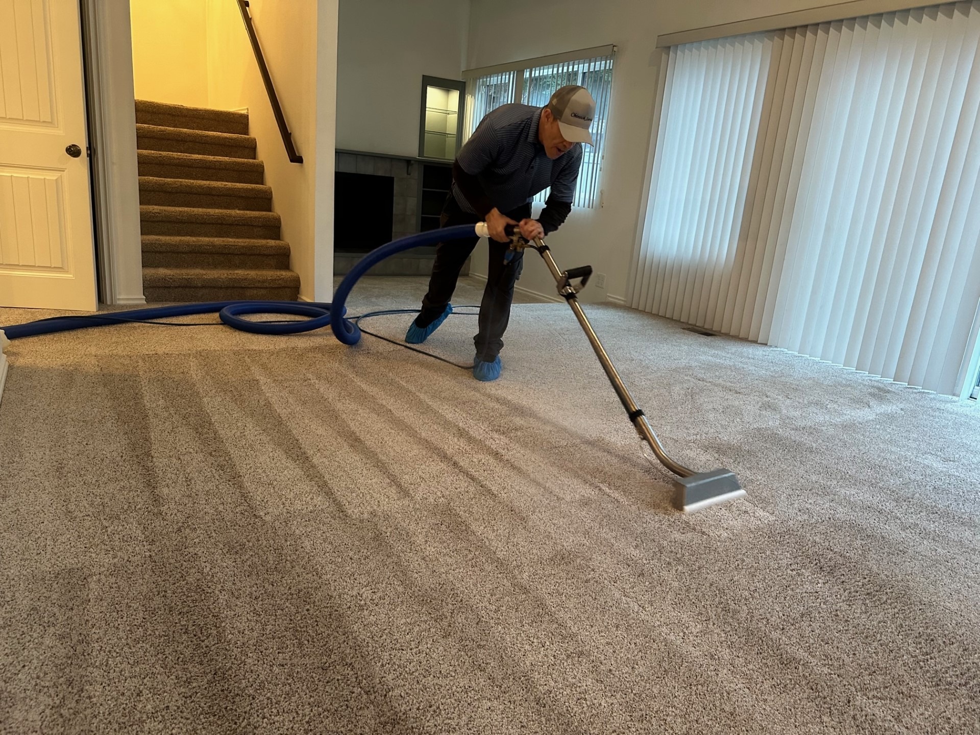 carpet cleaning by Chinook Services. Worker is cleaning carpets with truckmounted machine and wand on a local Seattle area home. The worker you can see is making the carpet look new.