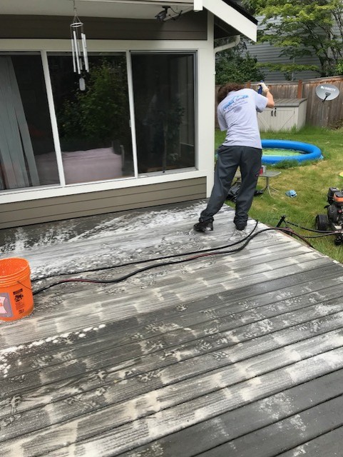 Worker from Chinook Services pressure washing a deck near Bellevue.