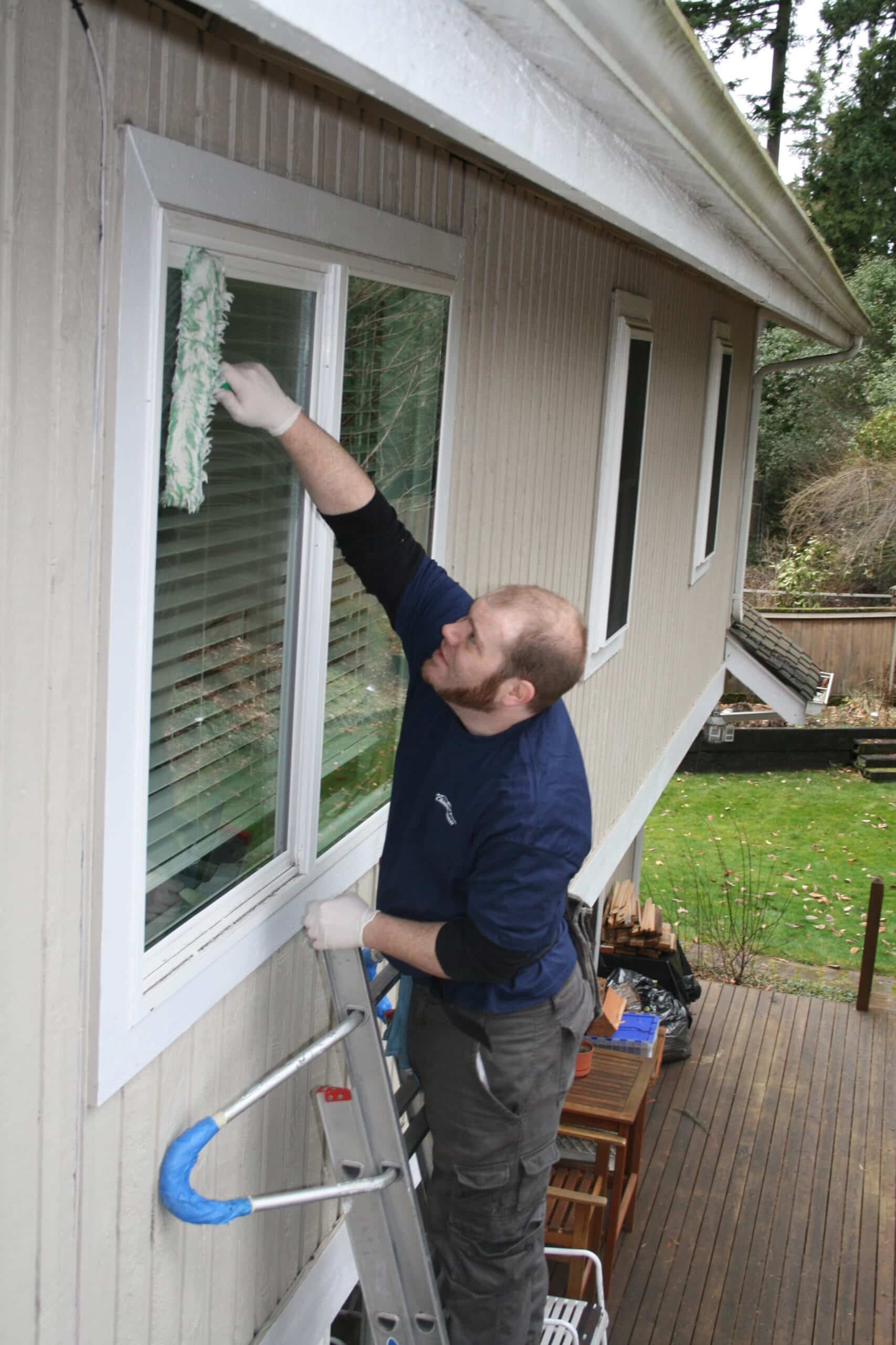 Hand cleaning exterior window Clyde Hill, WA home.