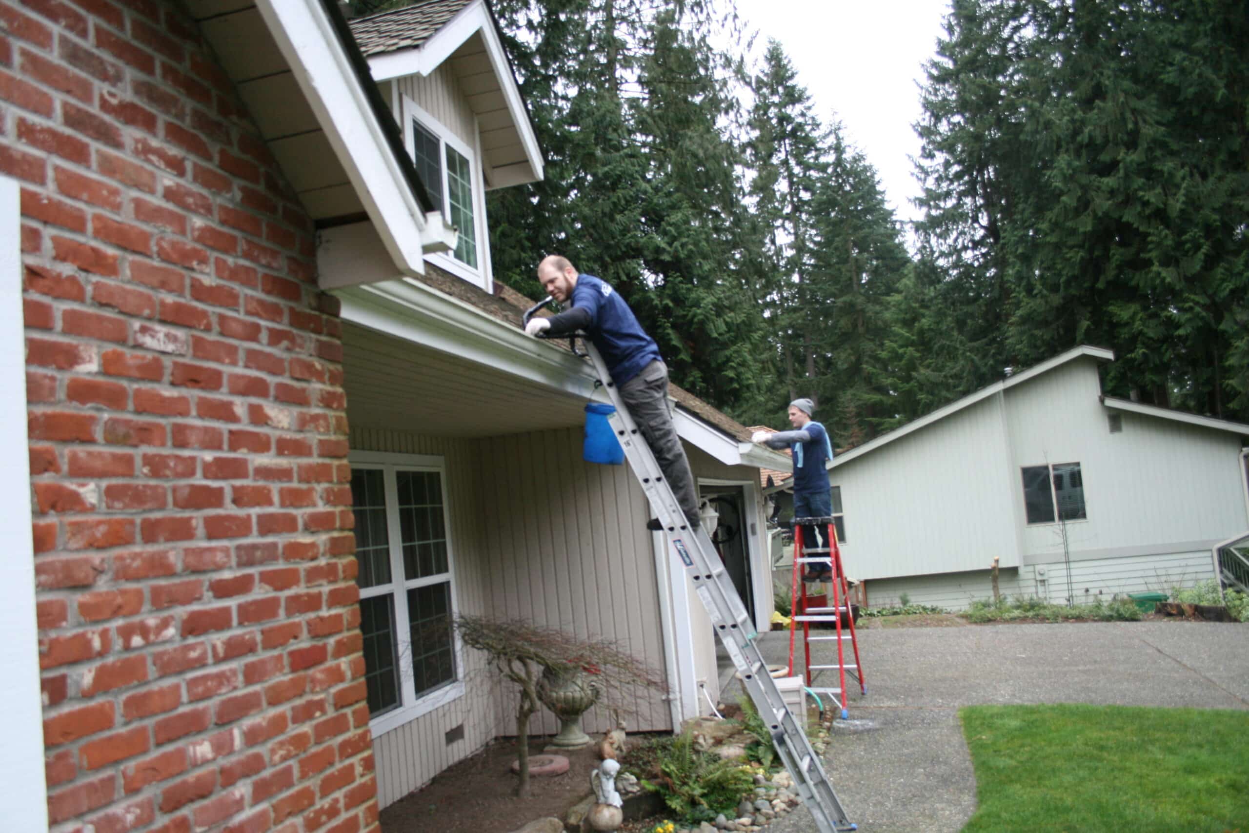 Two workers from Chinook Services cleaning gutters of home in Medina
