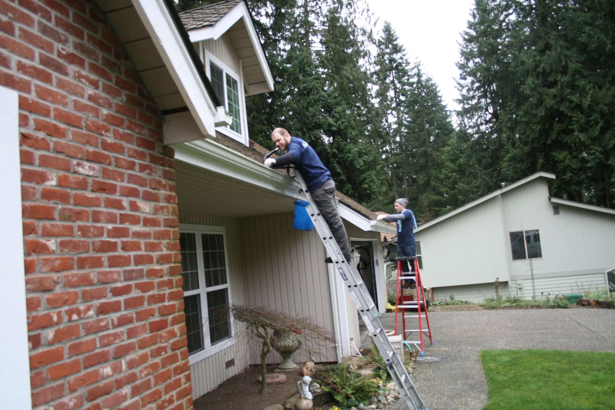 Two workers hand clean gutters by hand in Mukilteo, WA