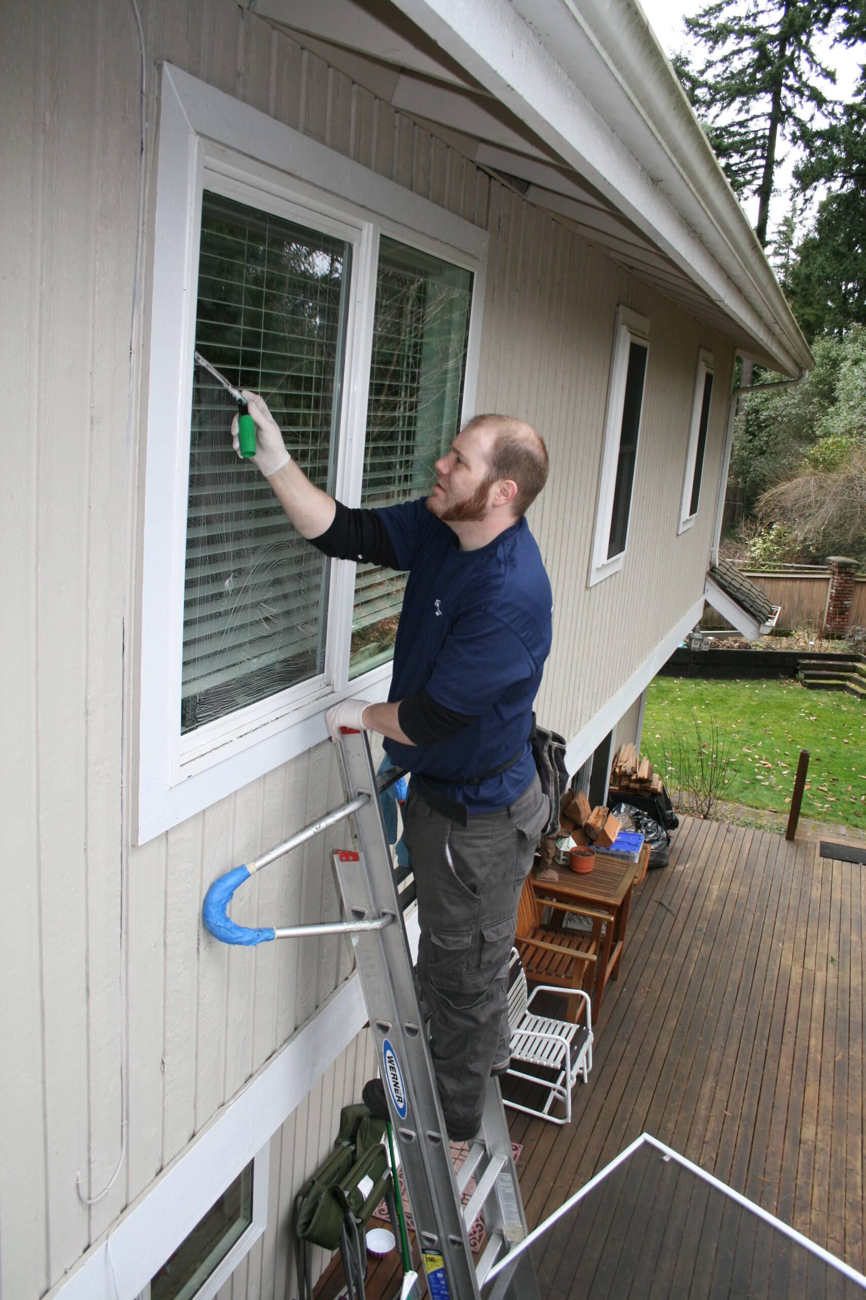Shoreline window cleaning service provider cleaing windows by hand using ladder
